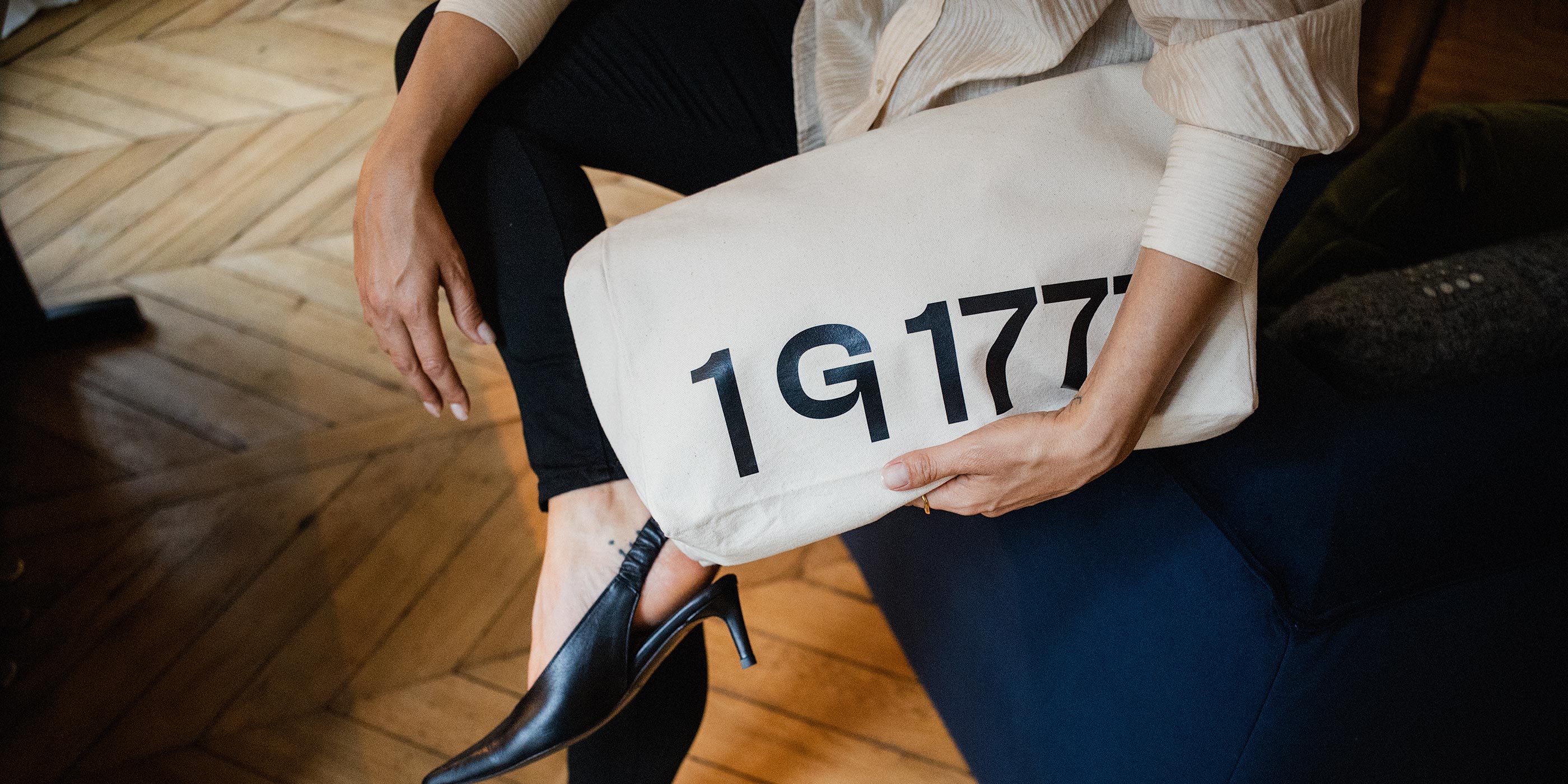 Close-up of a model wearing the 1G1777 canvas tote bag by Rosenstaub in a Haussmann apartment in Paris