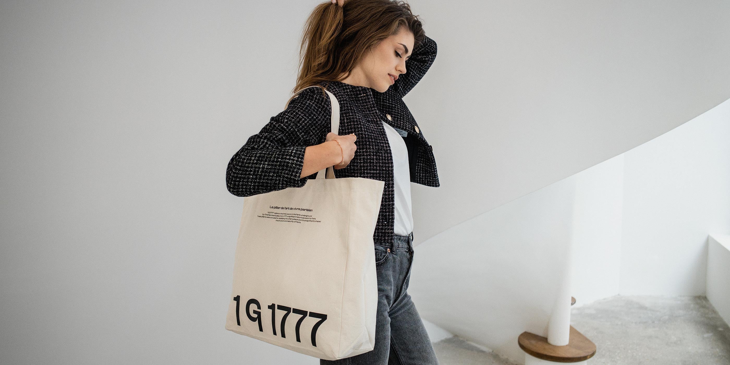 Model wearing the Rosenstaub 1G1777 Canvas Tote Bag in an all-white atelier in Paris, showcasing a blend of history and modern design.